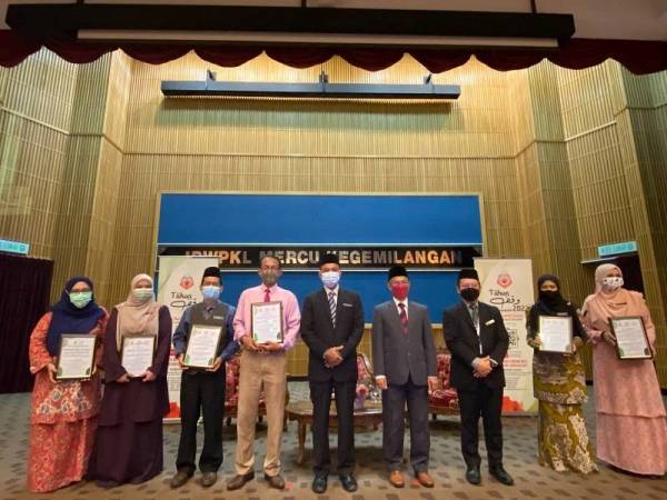 Ridzwan (empat dari kanan) menyampaikan sijil penghargaan kepada wakil lima sekolah rintis yang terlibat projek khas Wakaf al-Quran Pendidikan pada Selasa.
