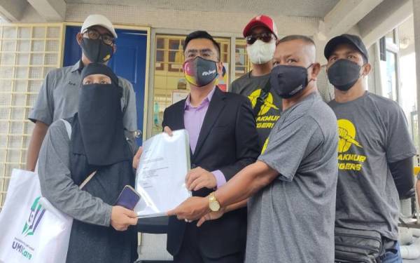Noora (kiri) menyerahkan memorandum kepada Mohd Hidayat (tengah) mewakili Amirudin di hadapan Bangunan Sultan Salahuddin Abdul Aziz Shah pada Rabu.