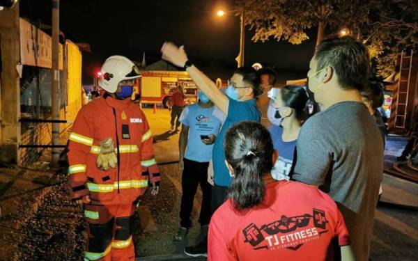 Tian Soon (tengah) berbincang dengan anggota bomba dan pemilik kedai selepas 15 lot kedai terbakar di Pasar Yong Peng Sdn Bhd, Jalan Meng Seng, Yong Peng, Batu Pahat, pada awal pagi Khamis.