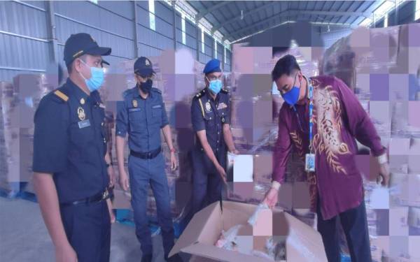 Rae Morn Verak (kanan) memeriksa tepung gandum yang dirampas di sebuah gudang di Kawasan Perindustrian Bukit Kayu Hitam, Kedah pada Rabu.