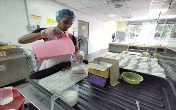 Pekerja, Wan Muhammad Yazid Wan Jusoh sedang membungkus santan yang telah siap diproses.