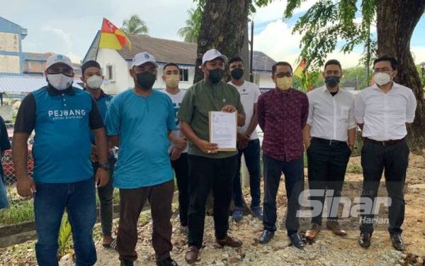 Akif (depan, tiga dari kiri) menunjukkan salinan laporan polis yang dibuat di Balai Polis Seksyen 6, di sini, pada Jumaat.