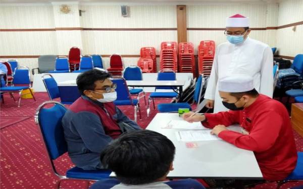 Abd Farid (berdiri) melihat proses pemberian vaksin kepada kanak-kanak di PPV Masjid Sultan Idris Shah II, di sini pada Jumaat.