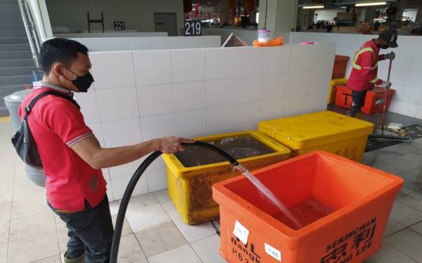 Seorang pekerja pembersihan dilihat mengambil air dari pili bomba susulan ketiadaan bekalan air sejak Jumaat.