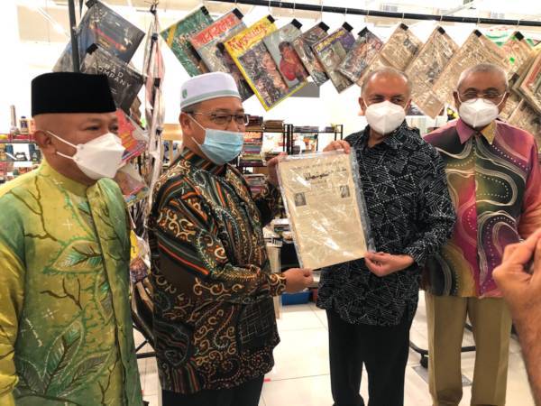 Ameer (dua dari kanan) dan Md Anizam Ab Rahman (dua dari kiri) menunjukkan akhbar Mingguan Kota Bharu bertulisan jawi yang dijual di Bazar Siti Hawa.
