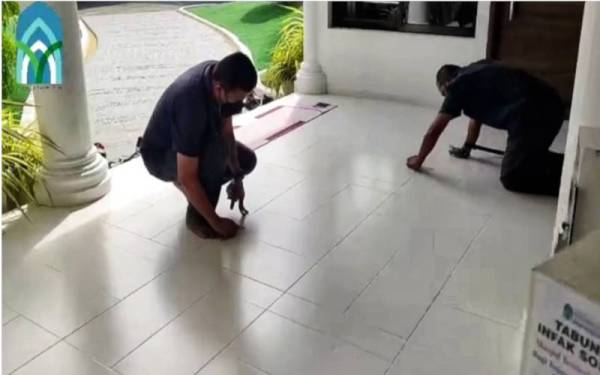 Petugas masjid menanggal dan membersihkan pelekat berikutan susunan sejadah dirapatkan. - Foto ihsan Masjid Temerloh Jaya