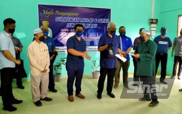 Hamzah (dua dari kanan) menyerah sumbangan kepada wakil masjid dan surau pada Majlis Penyampaian Sumbangan Masjid dan Surau DUN Batu Kurau pada Sabtu.
