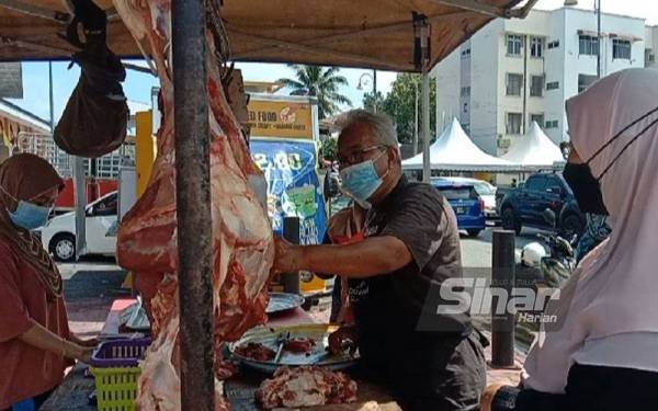 Seorang peniaga sedang melapah daging untuk dijual kepada pelanggan pada hari mantai.
