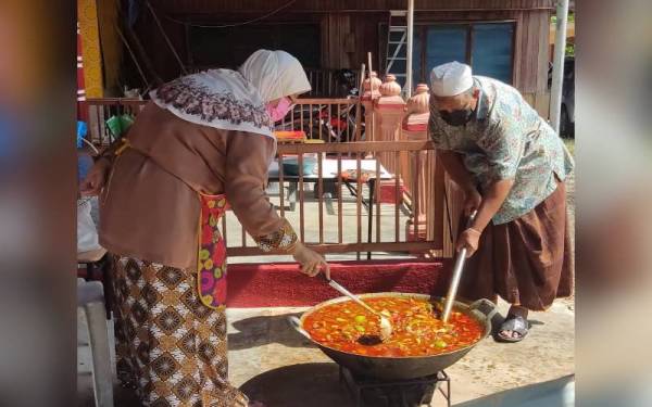 Nor Aini (kiri) bersama suaminya, Mohd mengacau acar limau yang perlu dimasak sekitar dua jam di Kampung Sungai Limau Dalam, Yan.