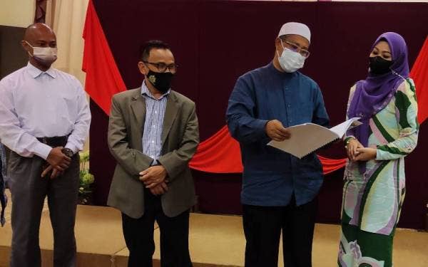 Mohd Nor (dua dari kanan) menunjukkan buku Garis Panduan Hiburan, Persembahan Kebudayaan, Pelancongan dan Sukan Negeri Terengganu yang mula diperkenalkan pada tahun 2020 kepada Lily Julia.
