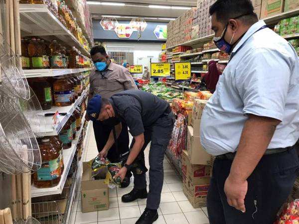 Pegawai penguat kuasa KPDNHEP Pulau Pinang sedang memeriksa bekalan makanan keperluan ketika menjalankan Ops Pantau 2022 pada Ahad.