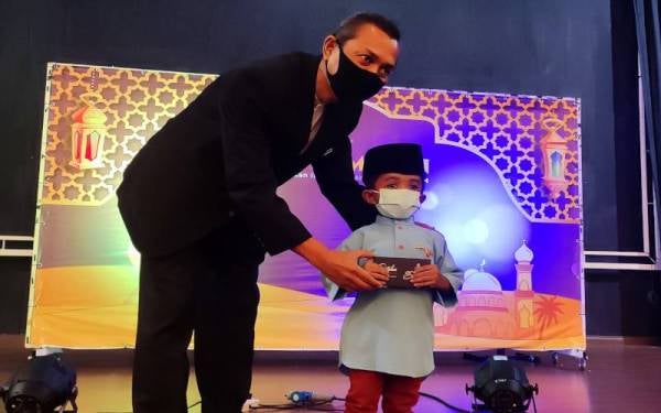 Engku Morris menyampaikan sumbangan kepada salah seorang anak yatim yang hadir berbuka puasa di Raia Hotel & Convention Centre Terengganu di sini pada malam Ahad.