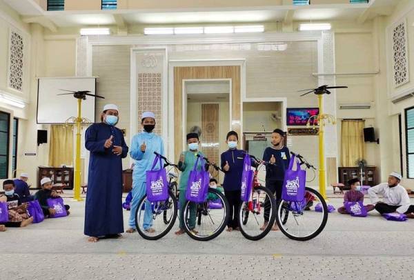 Hanapiah (kiri) merakam kenangan bersama empat kanak-kanak yang mendapat hadiah utama basikal.