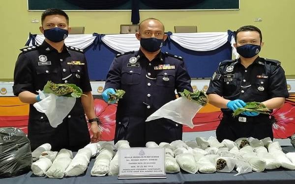 Anuar (tengah) menunjukkan daun hijau disyaki ketum yang dirampas di Taman Batik pada Jumaat.