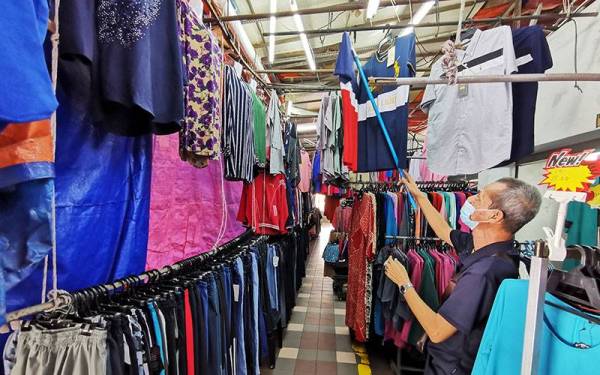 Azman menyusun rapi pakaian yang dijual di premisnya.