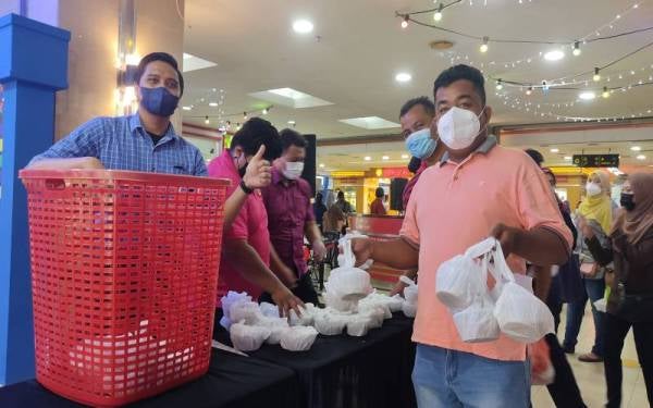Pengunjung mengambil bubur lambuk yang diedarkan secara percuma di Kompleks PKNS, Seksyen 14, Shah Alam pada Selasa.