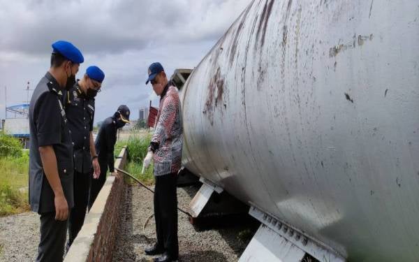 Saharuddin (kanan) melihat kesan proses pemindahan minyak diesel secara haram.