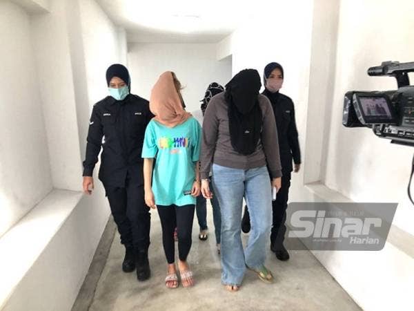 Anggota polis wanita (dua dari kanan) dan rakan suspek wanita (dua dari kiri) dikawal polis bagi mendapatkan perintah reman di Mahkamah Kota Bharu pada Khamis.