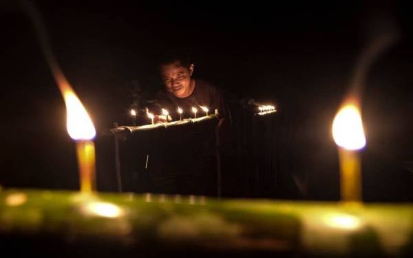 Mohamad Azmizan menyalakan pelita buluh ketika ditemui di rumahnya di Kampung Merchang di Marang. Foto Bernama
