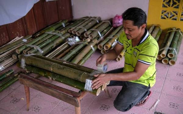 Mohamad Azmizan melakukan pembungkusan beberapa batang pelita buluh yang ditempah oleh pelanggan ketika ditemui di rumahnya di Kampung Merchang. Foto Bernama 