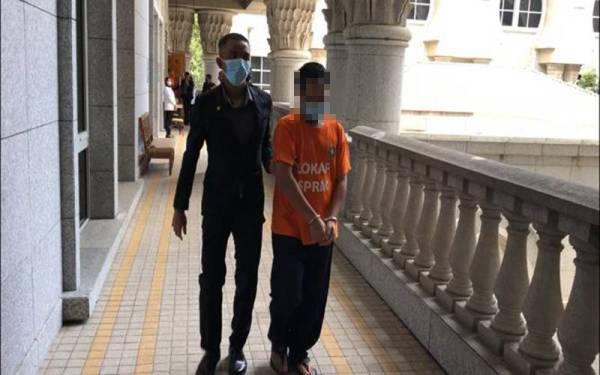 Salah seorang daripada individu yang ditahan diiringi pegawai SPRM ketika hadir ke mahkamah.