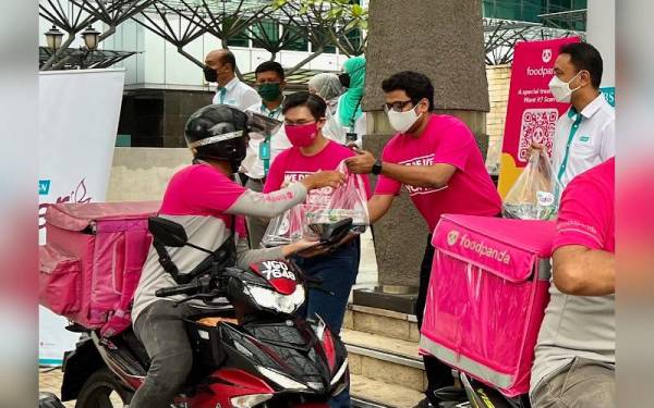 Kelvin (kiri) dan Subran (dua dari kiri) menyampaikan juadah berbuka puasa kepada penghantar makanan foodpanda.