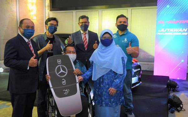 Mizan Masram (kiri) menyerahkan replika cek kunci kereta Mercedes kepada Saian Majid (duduk tengah) di Majlis Penyampaian Hadiah Al-Awfar.