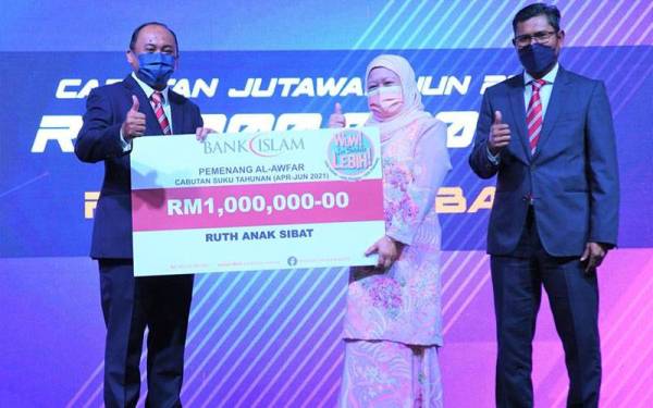 Mizan (kiri) menyerahkan replika cek RM1 juta kepada Ruth Anak Sibat (tengah) diiringi oleh Ketua Deposit dan Pengurusan Tunai BIMB, Mohd Noor Jab (kanan) di Majlis Penyampaian Hadiah Al-Awfar.