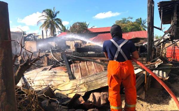 Anggota bomba memadamkan api yang masih bersisa dalam kebakaran membabitkan enam rumah di Tumpat.