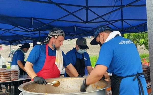 Ammar (kiri) membantu petugasnya membungkus juadah yang dijual di gerainya di Bazarena Stadium Shah Alam, Seksyen 13, di sini pada Sabtu.