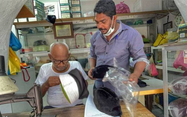 Haja Mohideen bersama menantunya, Abdul Kader menyiapkan songkok ditempah pelanggan.