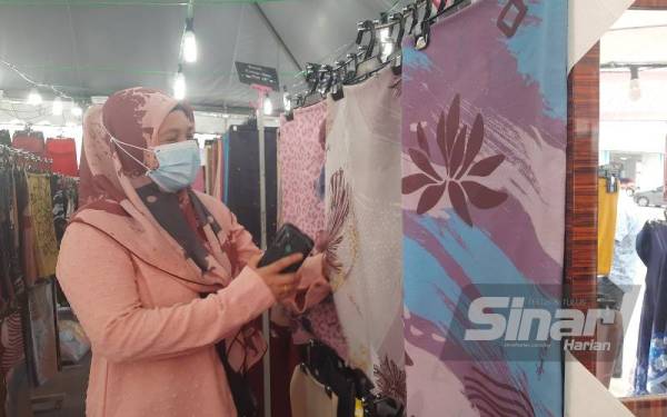 Norlida menyusun tudung yang dijual di bazar Aidilfitri Stadium di Kuantan sementara menunggu pelanggan yang didakwa semakin berkurangan.
