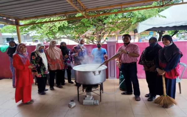 Abdul Kadir (empat kanan) bersama ahli KRT menyediakan bubur kanji untuk program agihan bubur kanji di Pusat Rukun Tetangga Kampung Berjaya, pada Isnin.
