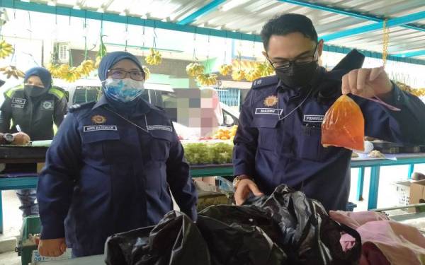 Hakimin (kanan) menunjukkan makanan dan minuman siap dibungkus ketika pemeriksaan dibuat di sebuah gerai buah-buahan.