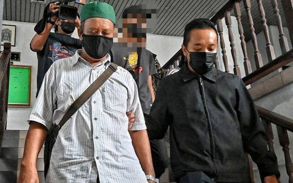 Zakaria (kiri) ketika dibawa keluar dari Mahkamah Sesyen Melaka pada Rabu.