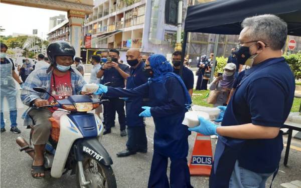 Mohammad Hanis dan Jawatankuasa Pengurusan Bank Rakyat mengedarkan bubur lambuk kepada pengguna jalan raya.