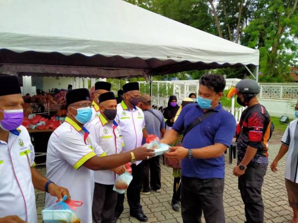 Mohamad Arib (dua dari kiri) mengagihkan bungkusan nasi beriani kepada warga Bandar raya Ipoh di perkarangan Masjid Sultan Idris Shah II di sini pada Rabu.