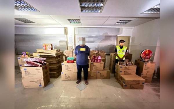 Suspek (kiri) bersama mercun dan bunga api yang dirampas dalam serbuan di Batu Pahat pada Rabu.