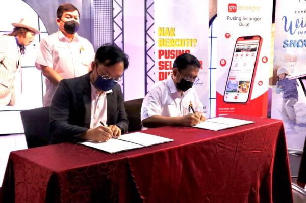 Loy Sian (belakang) menyaksikan majlis menandatangani MoU antara Tourism Selangor dengan TourPlus Technology bagi aplikasi Go Selangor.