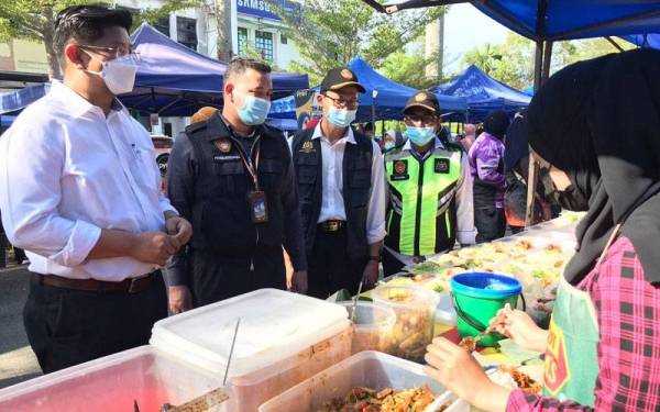 Dr Mohd Ridzuan (tengah) memeriksa tahap kebersihan peniaga dan premis di Bazar Ramadan Kampung Tengah, Sungai Abong, Muar pada Jumaat
