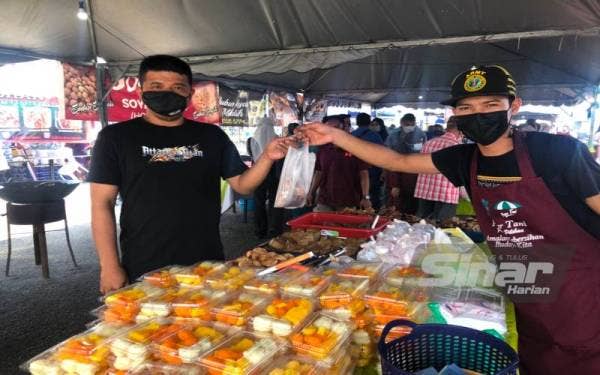 Pembantu gerai, Muhamad Afiq Mat Saufi (kanan) melayan pengunjung, Anuar Razak, 36, yang membeli kuih piana.