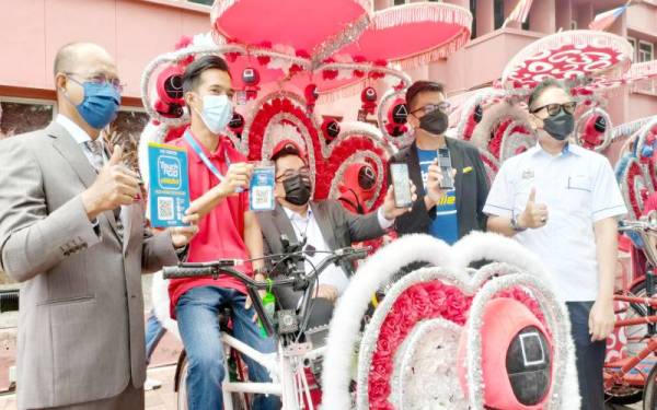 Johari (kiri) dan Sulaiman (tiga, kiri) menunjukkan e-wallet sebagai simbolik pelancaran penggunaan e-wallet ketika majlis Bacaan Yasin dan Penyampaian Sumbangan Hari Raya Aidilfitri kepada Pengayuh-pengayuh Beca Melaka di Muzium Rakyat, Banda Hilir, di sini, pada Isnin.