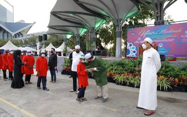 Zamani (dua dari kanan) menyampaikan sumbangan kepada anak-anak yatim pada Program Berbuka Puasa berkonsepkan ‘Iftar Ala Madinah’ dan Sembang Sahur Edisi Shah Alam Hari Tanpa Kenderaan Sabtu lalu.