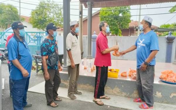 Mohd Zairi (lima,kiri) menyampaikan bungkusan lauk kepada penduduk yang datang di Surau Taman Asean 2, Malim.