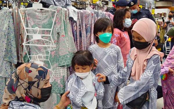 Salah seorang pegawai membantu memilih pakaian untuk tiga beradik daripada keluarga susah.