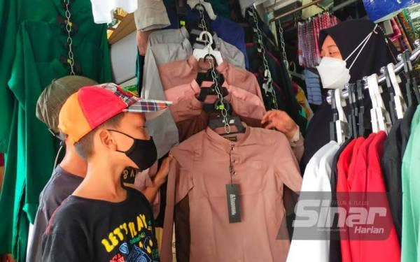 Siti Nur Aqilah (kanan) melayan dua pelanggan cilik di bazarnya yang terletak di hadapan Masjid Muhammadi, Kota Bharu.