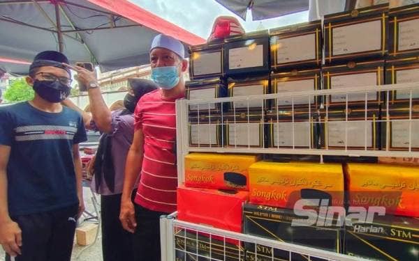 Wan Rosli (kanan) bersama isteri dan anak lelakinya sibuk memilih kopiah dan songkok yang akan dipakai Aidilfitri nanti.