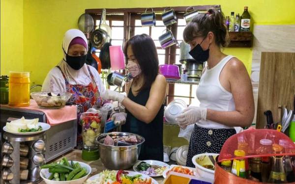 Dari kanan, Emily dan Katy belajar memasak masakan Melayu bersama Norhayati.