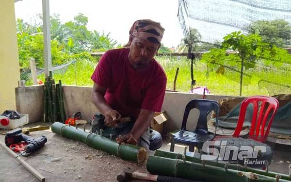 Ahmad Pirdaus memasukkan sumbu pada ruas buluh untuk dijadikan panjut.