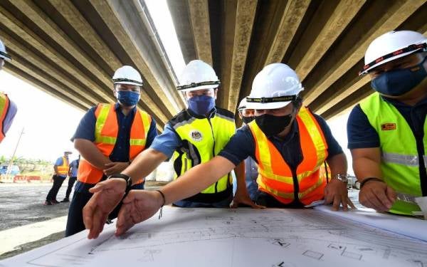 Arthur Joseph Kurup (dua dari kiri) diberikan penerangan mengenai pembinaan jejambat di Batu 32 oleh Ketua Penolong Pengarah Sektor Lebuhraya Pan Borneo Sabah Mohd Shamsul Nizam Abdul Wahid (kiri) ketika mengadakan lawatan kerja hari ini. Foto Bernama